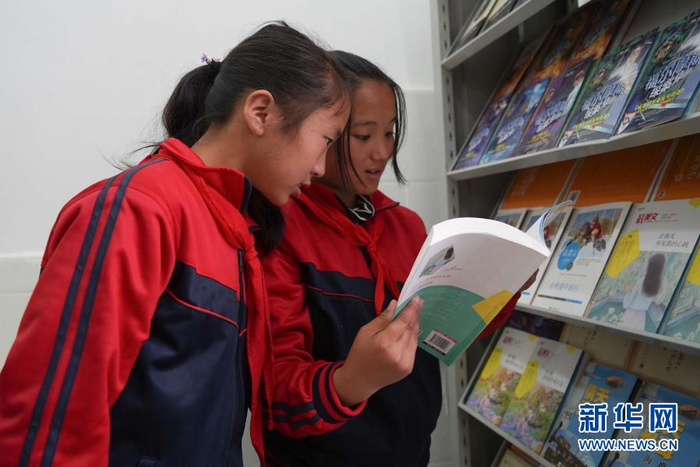 　　在四川省布拖县阿布泽鲁小学，海莫惹牛（右）和同学在新建的图书馆里阅读新书（6月23日摄）。新华社记者 胥冰洁 摄