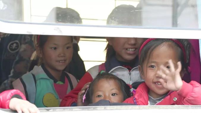 彝族的小朋友们好奇地看着窗外的世界