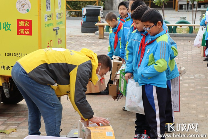 干巴精公司工作人员对学生们提供的硬纸板、旧书报等进行称重回收