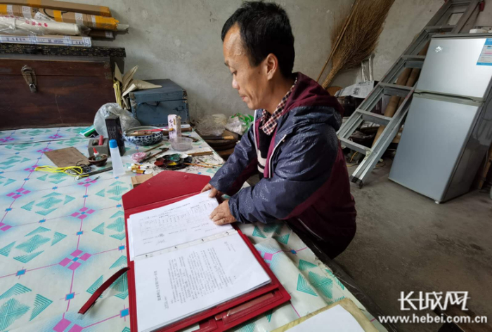 边学强在翻看自家的“小红兜”。长城网记者 郭庆敏 摄