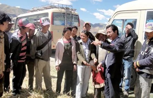 　　尼玛扎西（右三）在田间给农民讲解青稞种植技术。　资料图