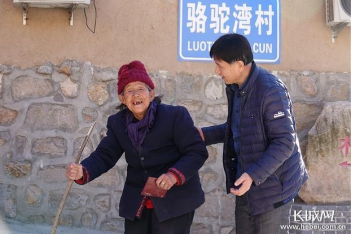 黄文忠（右）搀扶着老人去领分红。 长城网记者 胥文燕 摄