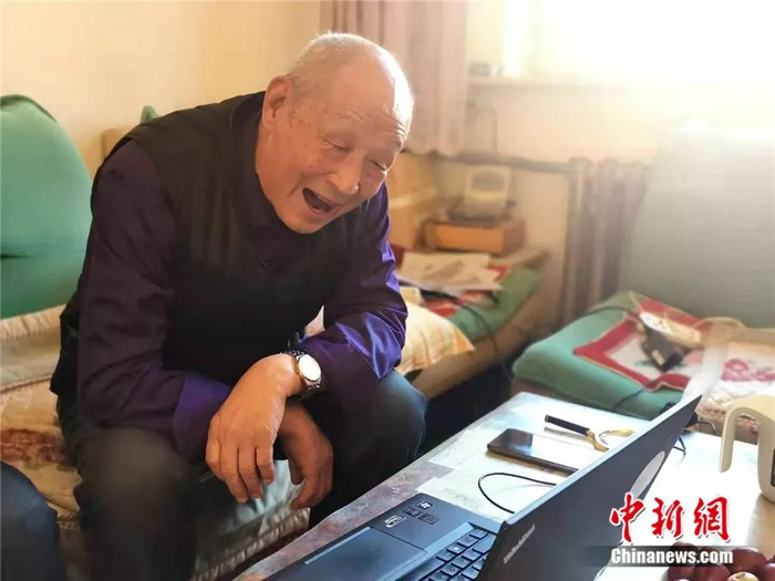 图为视频对话中的齐振荣老人，说到高兴之处开怀大笑。 乌娅娜 摄