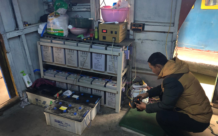  胡存库在船上给灯充电。为了用上稳定的电源，他在两年前购入了这些蓄电池。新京报记者 韩沁珂 摄