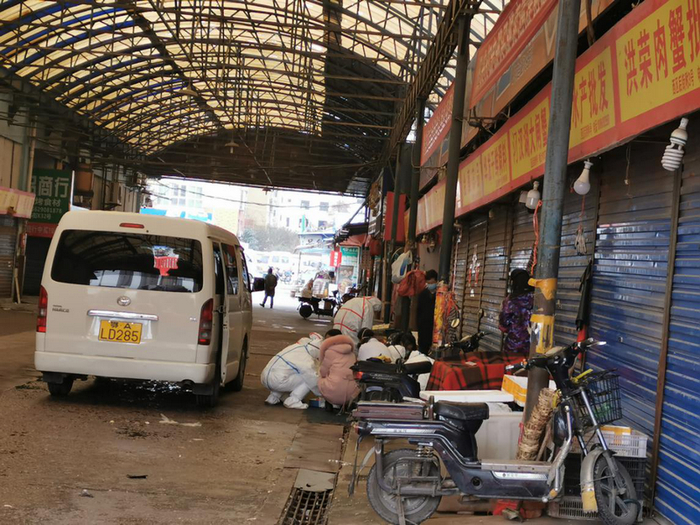 （两名身着防护服的工作人员正对水产商户进行采样。本报记者 张家振/摄影）