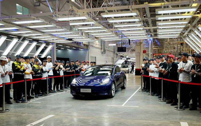 （一辆特斯拉Model 3汽车驶入交付仪式现场，图片来源：新华社。）