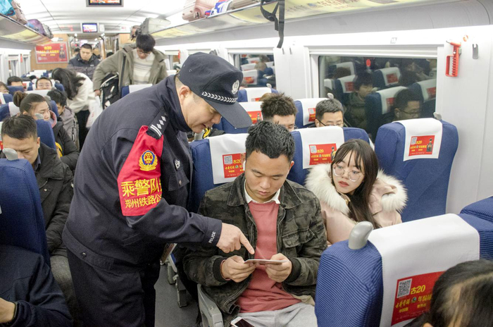 图为郑州铁路公安处乘警在列车上向旅客介绍安全常识