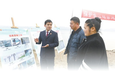 重庆市渝北区人民检察院的工作人员（左）在渝北区洛碛镇长江码头向群众介绍“长江禁捕”相关知识。 新华社记者 王全超摄