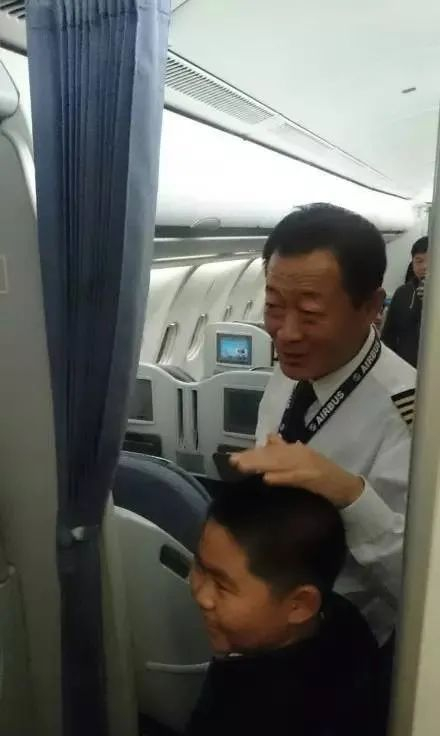 ▲ 贺机长摸着一个小男孩的头，两人似乎在说着什么，男孩笑得很灿烂。