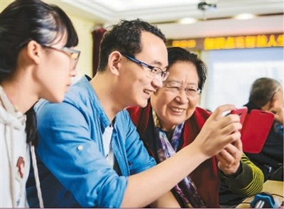 　　王士兰老人（右）在学习智能手机的使用方法。 　　罗 旭摄