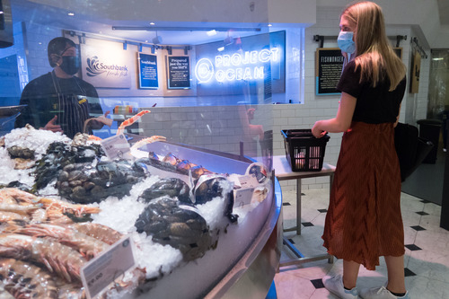 7月24日，一名戴口罩的顾客在英国伦敦一家百货公司的餐饮区挑选生鲜。新华社发（蒂姆·爱尔兰摄）