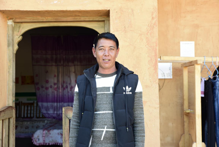 吉好也求在新居前留影（央视网记者 王静远 摄）