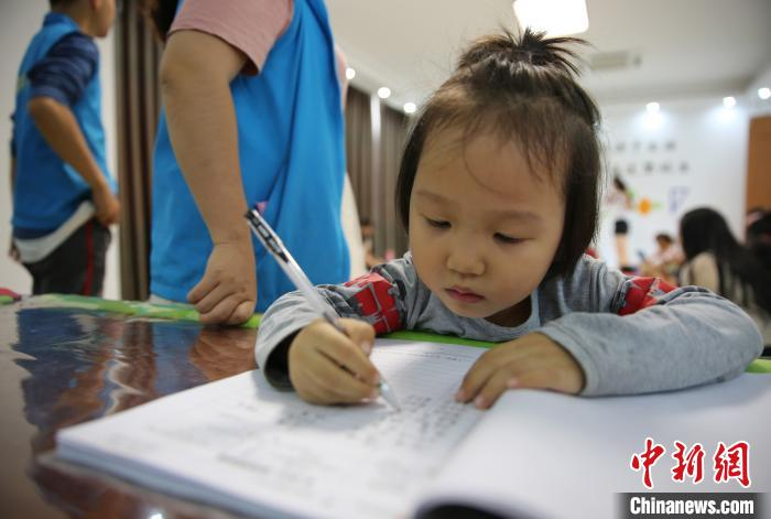 朱雨茉在签到表上签下自己名字。　王晓斌 摄