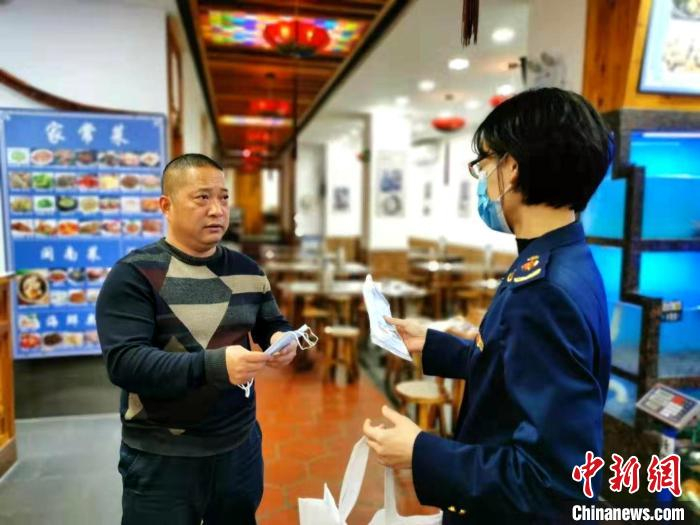 市场监督管理人员提醒经营者落做好佩戴口罩等防护措施。　供图 摄
