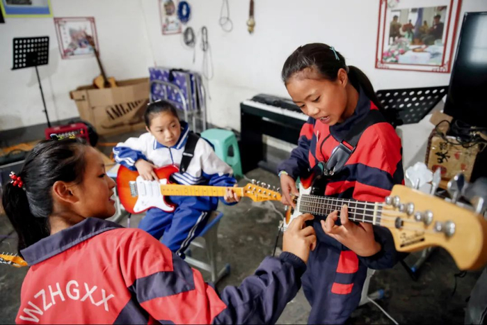 2020年7月1日，贵州六盘水市钟山区大湾镇，海嘎小学六年级“未知少年”乐队主吉他熊婷 （右）和其他成员在练习。图/中新