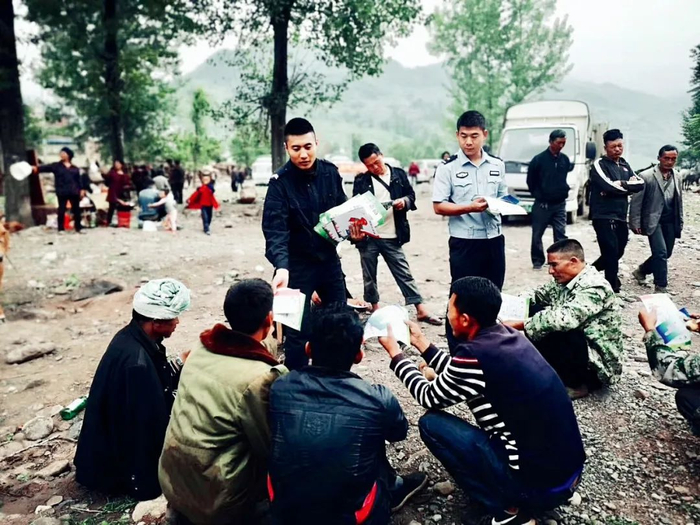 四川凉山彝族自治州美姑县牛牛坝乡，热口阿觉村第一书记王诏 （身着浅色警服）和同事在向村民散发禁毒防艾的宣传单。图/受访者提供