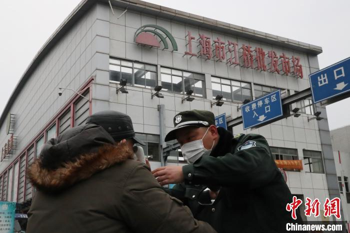 保安为进去市场的商户测量体温。　张亨伟 摄