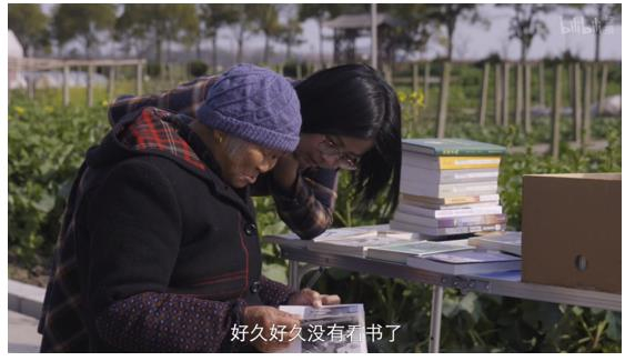 老奶奶在书摊前看起了书