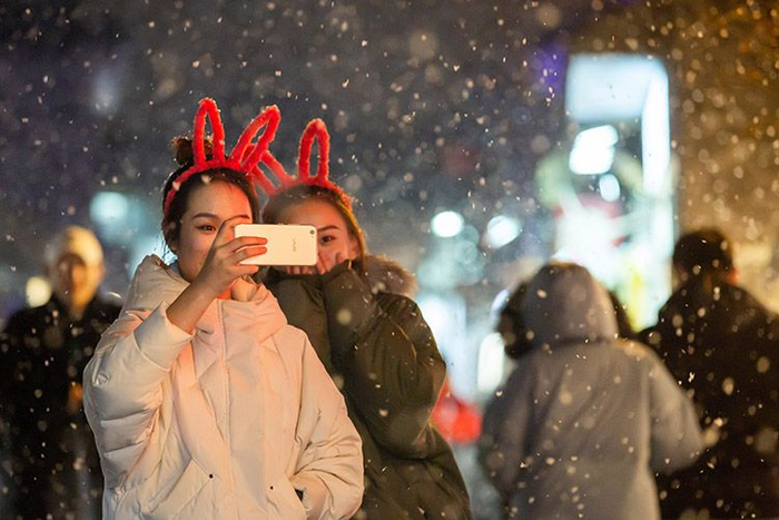 烟袋斜街，一对女青年在雪中合影。
