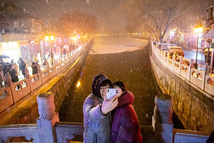 银锭桥上，游客在雪中留影。