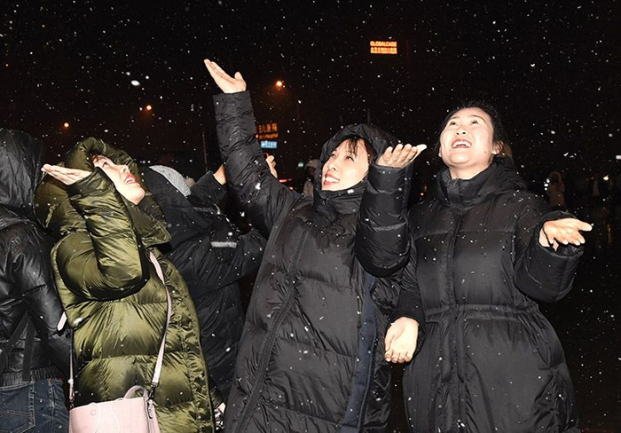 朝阳区合生汇门前，市民用手接着雪花。