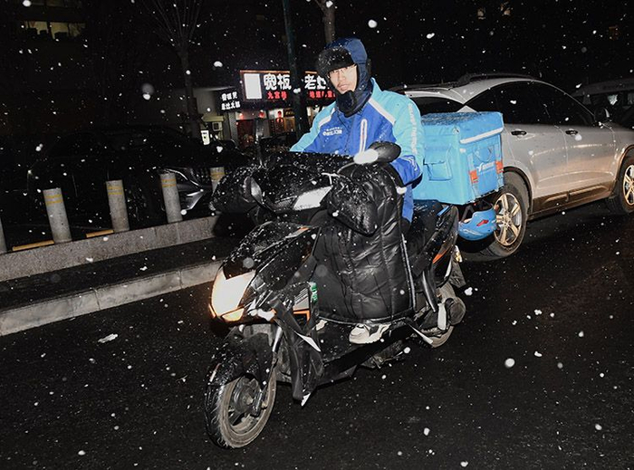 朝阳区东九路，外卖小哥冒雪送餐。