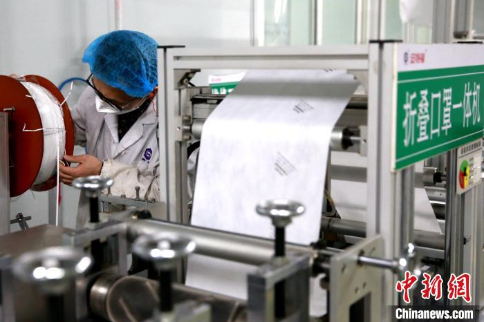     工作人员正在操作折叠口罩一体机，确保满负荷生产。　梁犇　摄