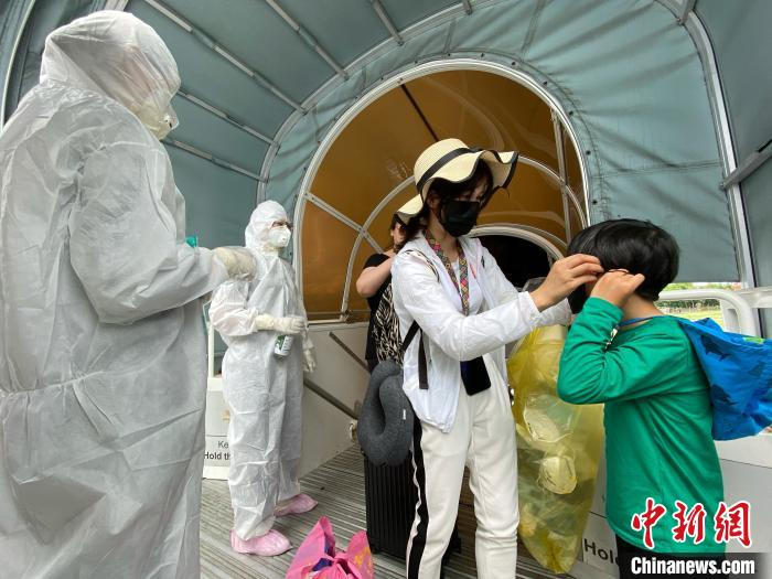 登机前机组人员对旅客进行基本消毒和更换全新口罩 东航供图 