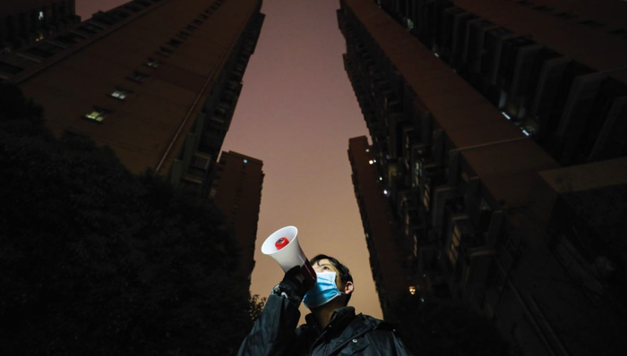 　　1月28日晚，武汉市江汉区唐家墩街道西桥社区的一个小区里，社区安保员李国华拿着小喇叭喊话让居民注意安全注意防疫。 摄影/长江日报 陈卓