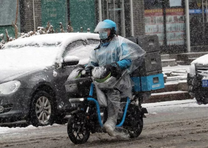 ▲2月14日，北京降雪后，快递小哥用塑料袋做成“雨衣”。新京报记者 王远征 王贵彬 摄