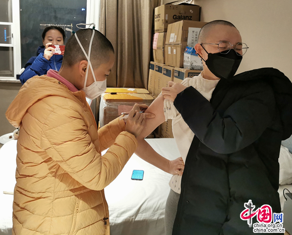 曾萍（左）帮同事打提高免疫力的针。受访者供图