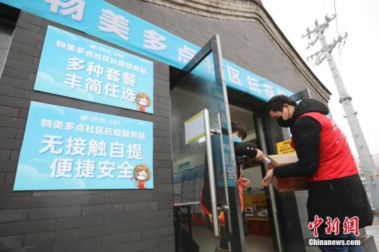 资料图：送货的工作人员在服务站门口进行体温测量。 中新社记者 盛佳鹏 摄