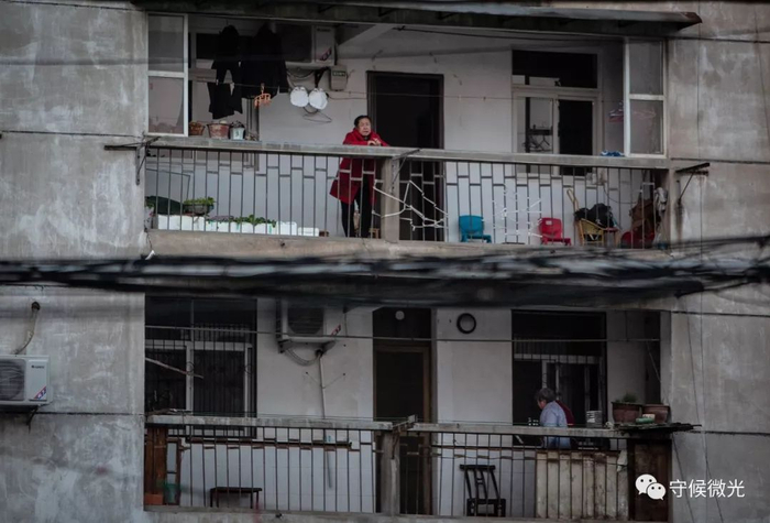  2月17日，湖北省孝感市，一栋老居民楼内，居民站在临街的楼道上向外张望。中青报·中青网记者 李峥苨/摄
