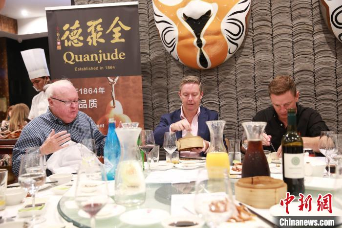 主持人与顾客一起品尝烤鸭。　樊南 摄