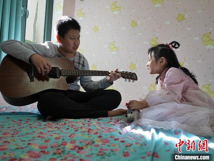 妹妹很喜欢听哥哥弹吉他 苍雁 摄