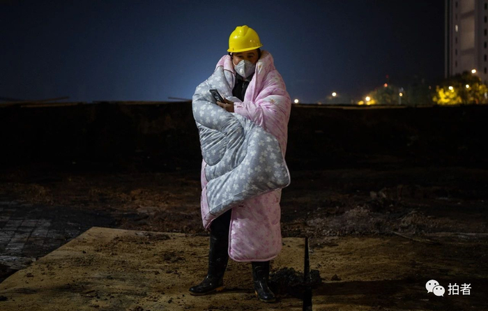  △&nbsp;凌晨，雷神山医院建设工地现场，由于夜间气温较低，工人身披被褥看护工地。摄影/拍者许星星