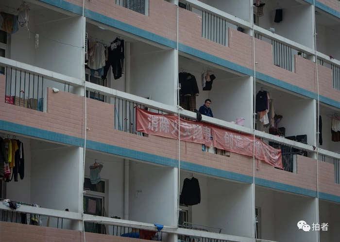 △&nbsp;武汉船舶职业技术学院一栋已被征用为定点隔离点的学生宿舍楼里，一名患者在阳台上透气。摄影/中青报·中青网记者李峥苨