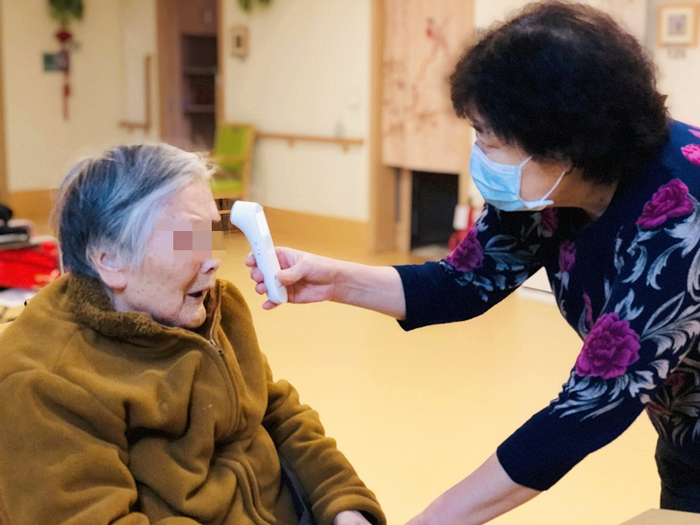 　　养老院封闭后，院长于金秀加入到一线护理行列，为老人进行每日体温测量是工作内容之一。受访者供图