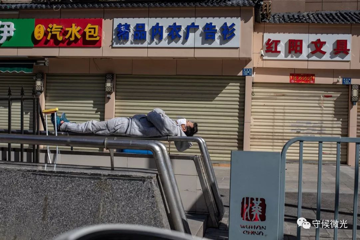 2月16日，湖北省武汉市，利济路上，一名市民躺在栏杆上晒太阳。中国青年报&nbsp;李隽辉/摄