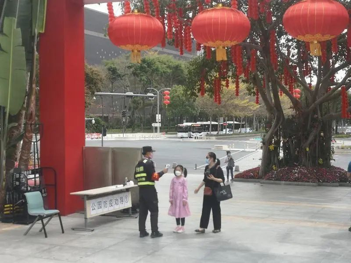 ▲在莲花山公园入口，工作人员对入园游客进行体温测量。