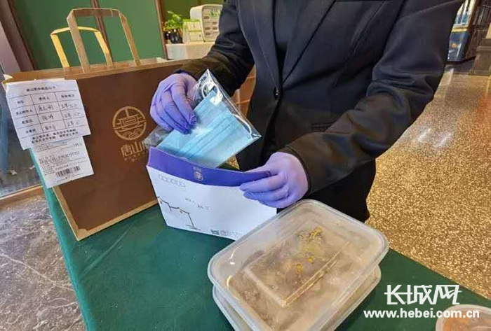 唐山宴工作人员戴着手套为外卖打包，并附赠一次性口罩。唐山宴 供图