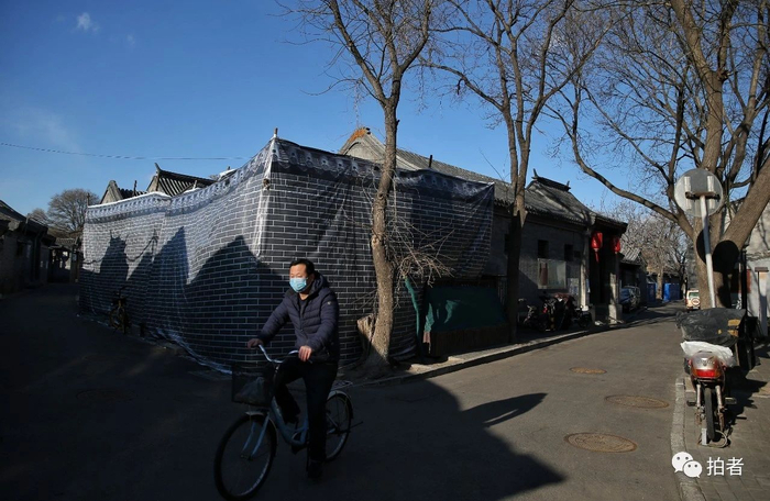  △&nbsp;3月1日，南官房胡同，一位居民戴着口罩骑行穿过胡同。摄影/新京报记者薛珺