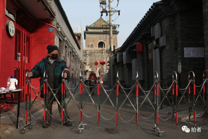  △&nbsp;2月25日，旧鼓楼大街，一位工作人员在铃铛胡同值守。因疫情防控需要，胡同口设置了24小时值班岗，进出居民须出示出入证，测量体温后方可通行。摄影/新京报记者薛珺