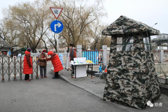  △&nbsp;2月27日，后海小桥南侧路西口，两位志愿者在检查居民的体温和出入证。摄影/新京报记者浦峰