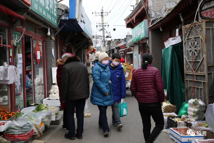  △&nbsp;2月27日，大栅栏街道三井社区，居民戴着口罩在胡同里采买物资。摄影/新京报记者郑新洽