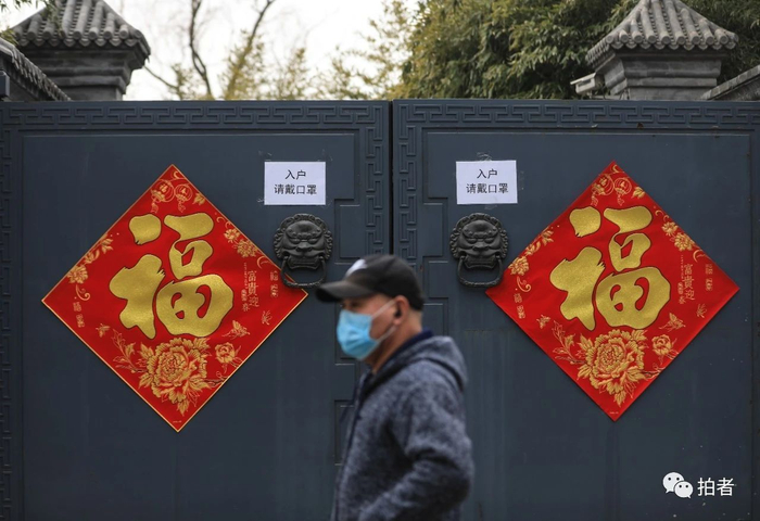  △&nbsp;2月27日，后海北沿，戴口罩的行人从贴有福字和“入户请戴口罩”的提示标语前经过。摄影/新京报记者浦峰