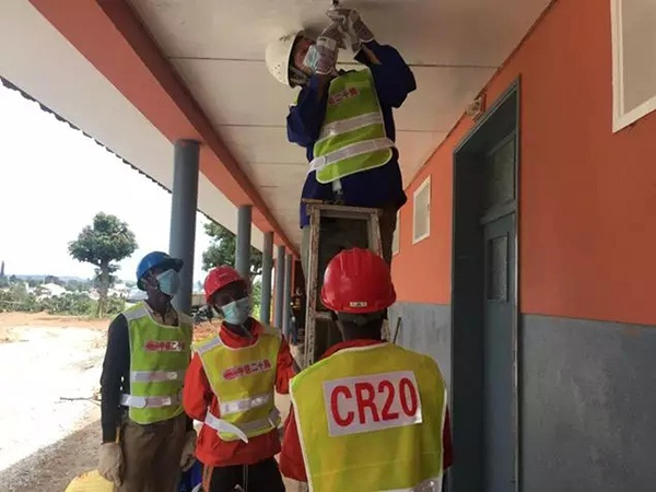 中外施工人员正在安装廊灯。