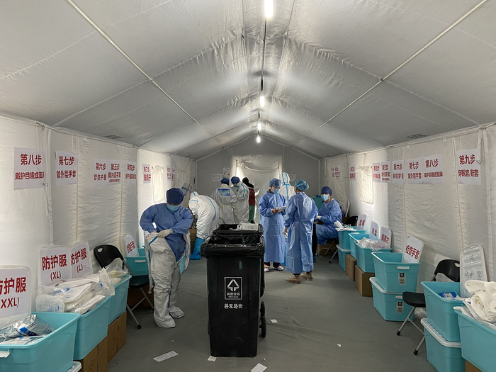 医护人员正在穿防护服。其中一位的衣服上写着“春天来了”。 澎湃新闻记者 赵思维&nbsp; 图