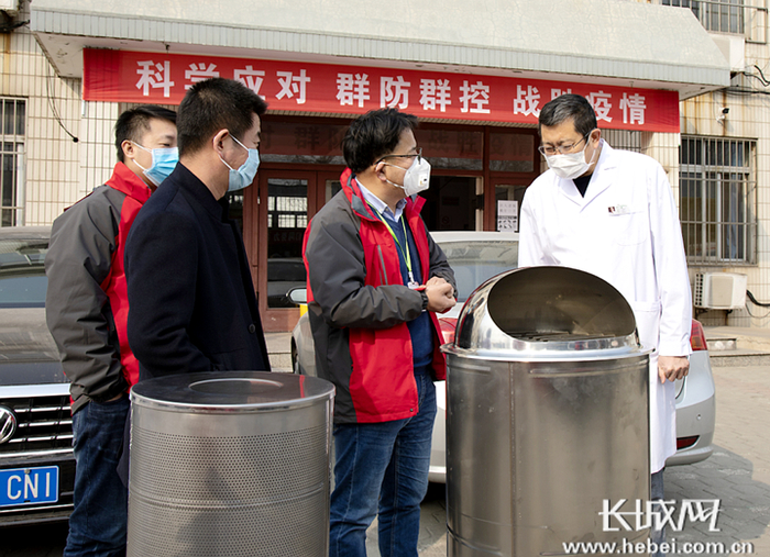 贾世俊（右二）向唐山市传染病医院院长介绍新研发的两款医护人员负压防护设备。