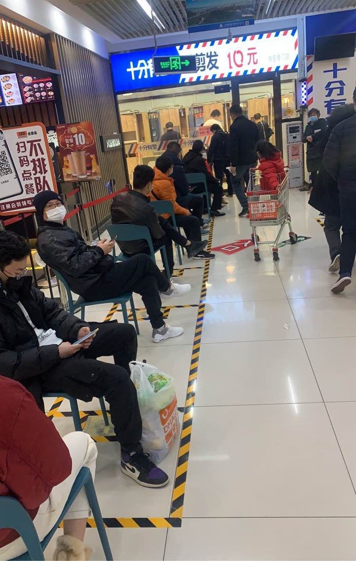  物美10元快剪店门前，顾客按一米线间隔排队。摄影/新京报记者 陈琳